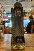 rectangular bottle with diamond shaped indents and a black top and silver letters that read 1800 Cristalino Anejo