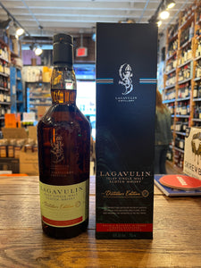 Lagavulin Distillers Edition Islay Single Malt 750ml a tall round shouldered clear glass bottle with a light green label and dark green top next to a tall squared dark blue box