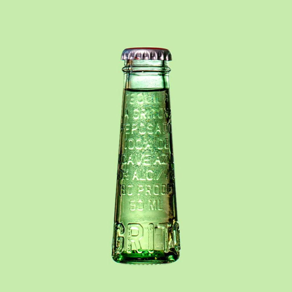 La Gritona Reposado 50mL a small clear glass bottle shaped like a vial with a tin bottle cap