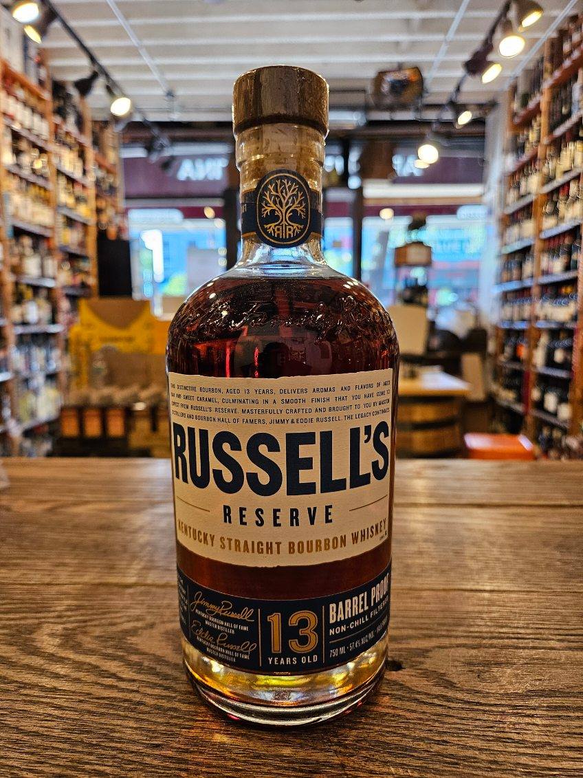 Russells Reserve 13 Year Old Barrel Proof 750mL a short squat round shouldered clear glass bottle with a white and blue label and wooden top