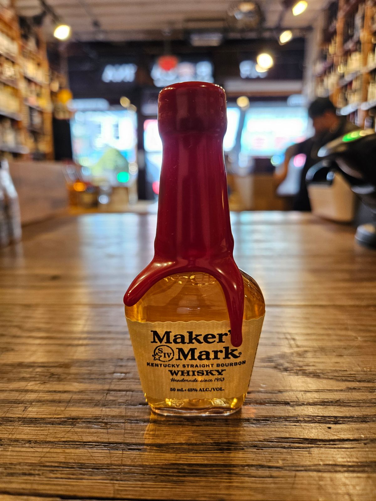 Makers Mark 50mL a small plastic clear bottle with a beige label and a red wax top