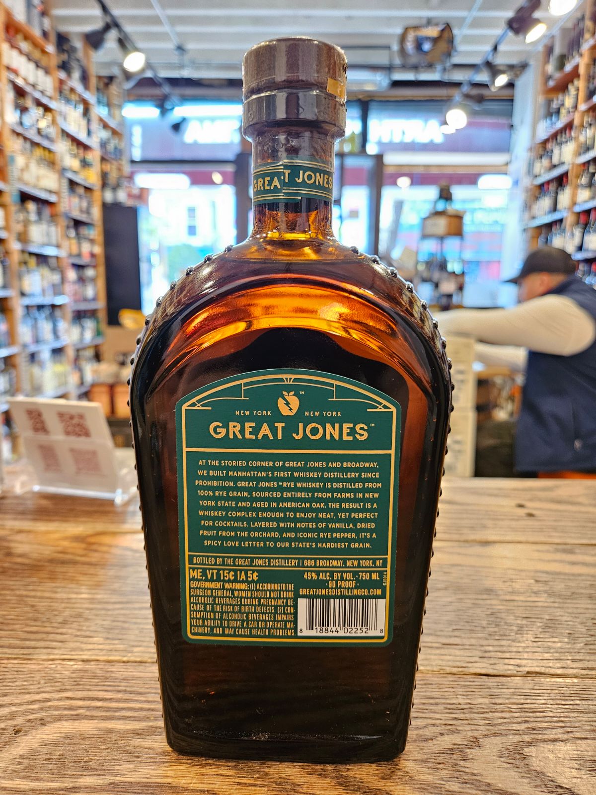 Great Jones Rye 750mL the backside of a dark flat and high rounded bottle with a green and gold label