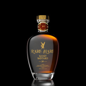 Rare Hare Lucky Bastard 30YR Rye 700mL a oval shaped short clear glass bottle with golden lettering and a golden top