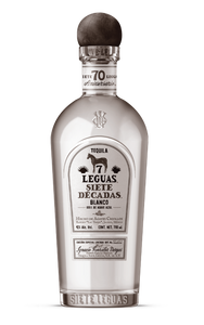 Siete Leguas Siete Décadas Blanco 750ml a large round shouldered clear glass bottle with a white label and round wooden top