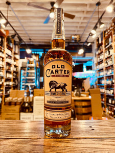 Old Carter Straight American Whiskey Batch 10 750mL a large tall high shouldered clear glass bottle with a beige label and the image of a horse on it with a wooden topper