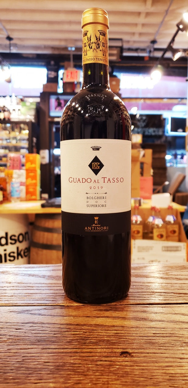 Guado Al Tasso 2019 Bolgheri a tall dark wine bottle with a white label and a golden top