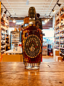 Michter's Rye 10yr 750mL a clear glass bottle with rounded shoulders and black label with a net around the bottle and a wax black top