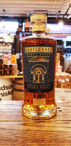 Castle & Key Small Batch 6 750mL a rounded wide shouldered clear bottle with a blue and gold label with a golden top