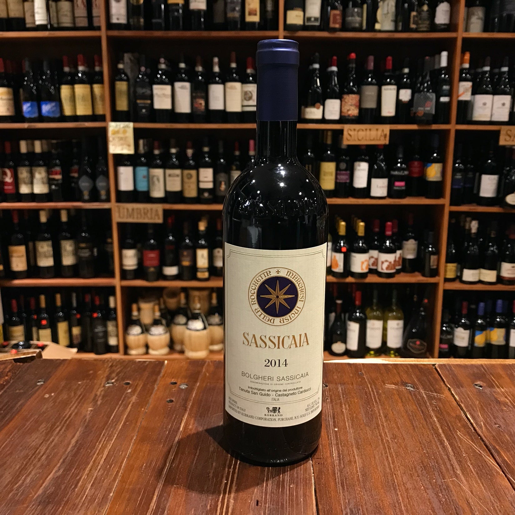 Sassicaia 750mL 2020 a dark glass wine bottle with a large white label and a blue top