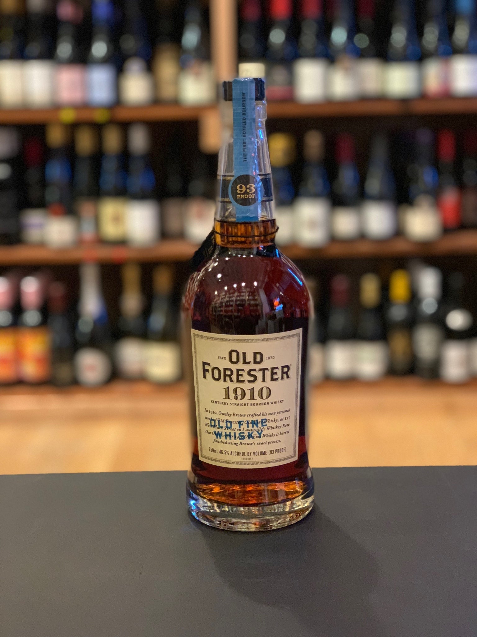 Old Forester 1910 93º Old Fine Whisky 750mL a round shouldered clear glass bottle with a beige label and light blue label top