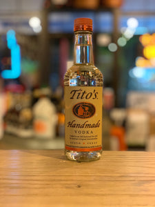 Tito's Handmade 1L Vodka a clear glass bottle with yellow label and a rust color top