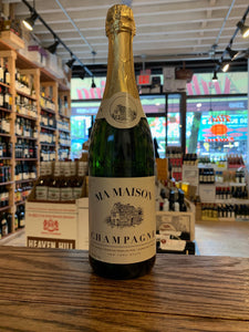 Ma Maison Champagne 750mL a dark green clear champagne bottle with a white label and golden top