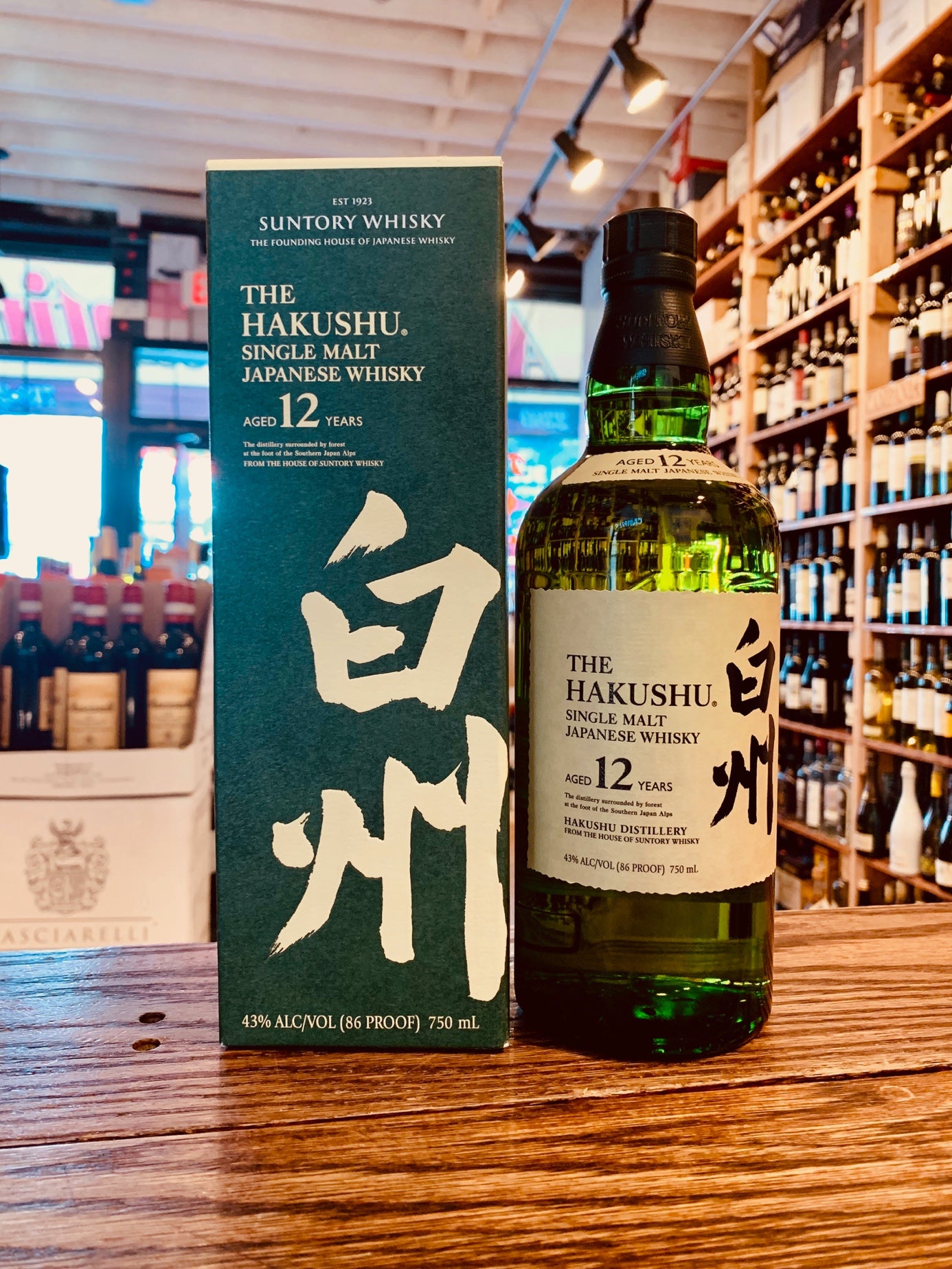 Hakushu Single Malt 12 750mL a tall green box with white lettering next to a green clear glass high rounded bottle with a short neck white label and black top