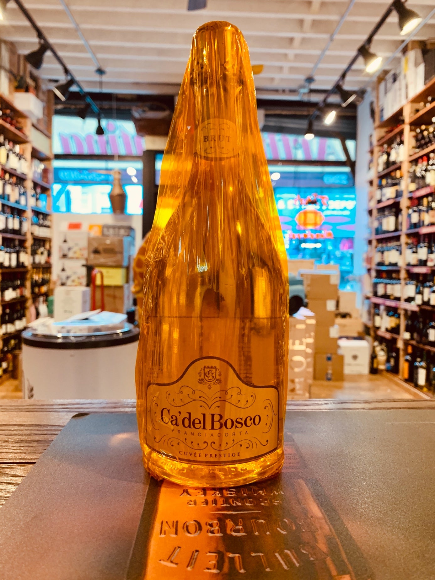 Ca del Bosco Franciacorta 750mL gold clear champagne bottle with a gold transparent plastic wrap around it.