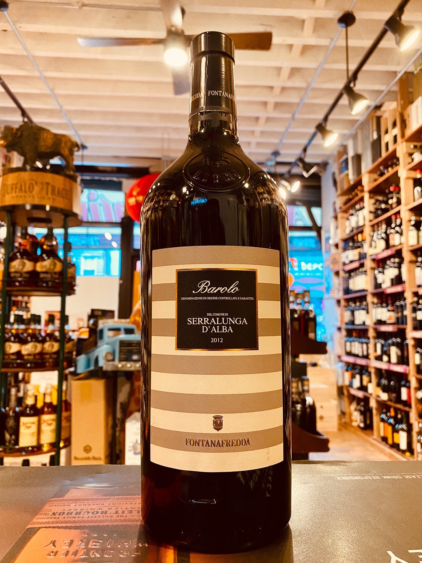 Barolo Serralunga 2012 1.5L a large black wine bottle with a beige and white striped label.