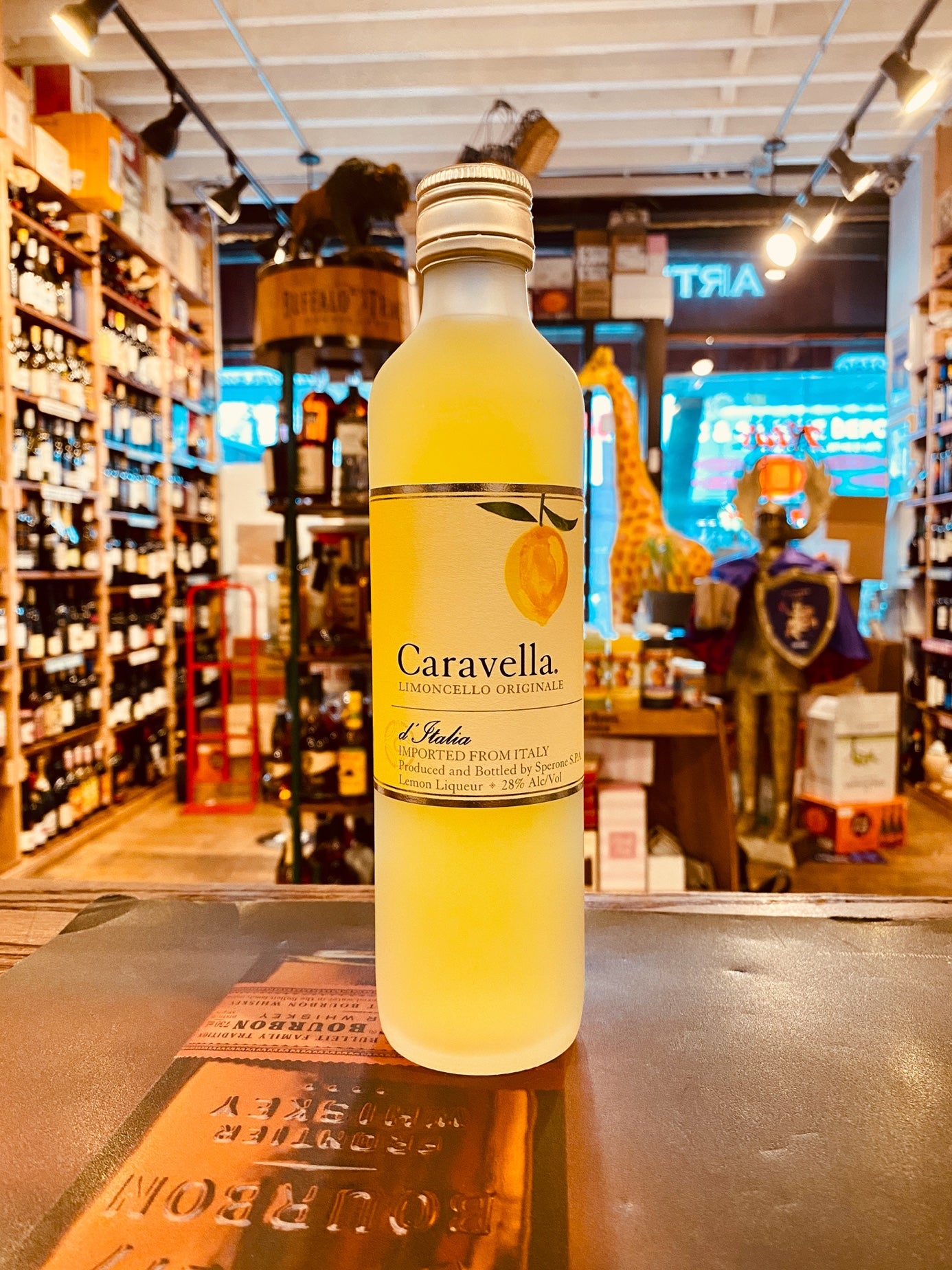 Caravella Limoncello 375 mL a small clear frosted slender glass bottle with yellow liquid and a beige label and silver top