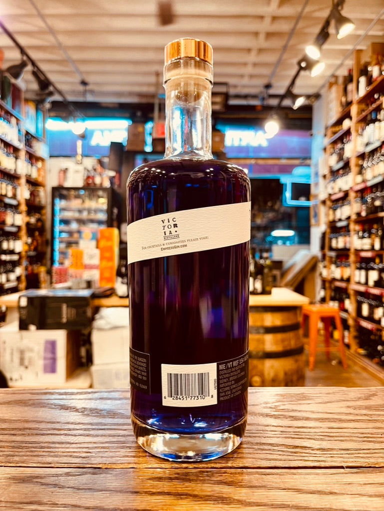 Empress 1908 Indigo Gin 750mL the backside of a clear cylinder shaped bottle with purple liquid and white label and gold top