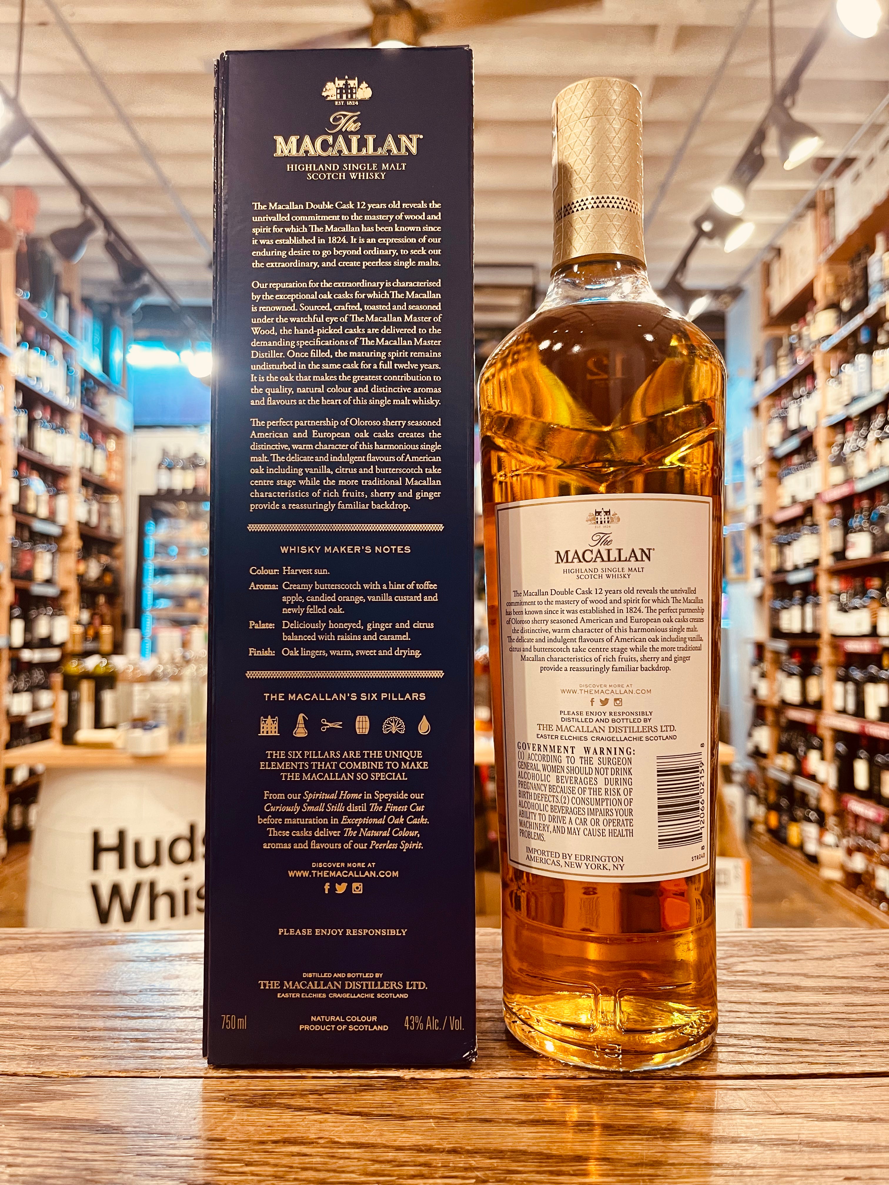Macallan 12yr Double Cask 750ml the backside of a blue box with white lettering next to a tall slender clear glass bottle with a white label and golden top