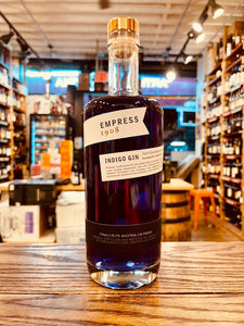 Empress 1908 Indigo Gin 750mL a clear cylinder shaped bottle with purple liquid and white label and gold top