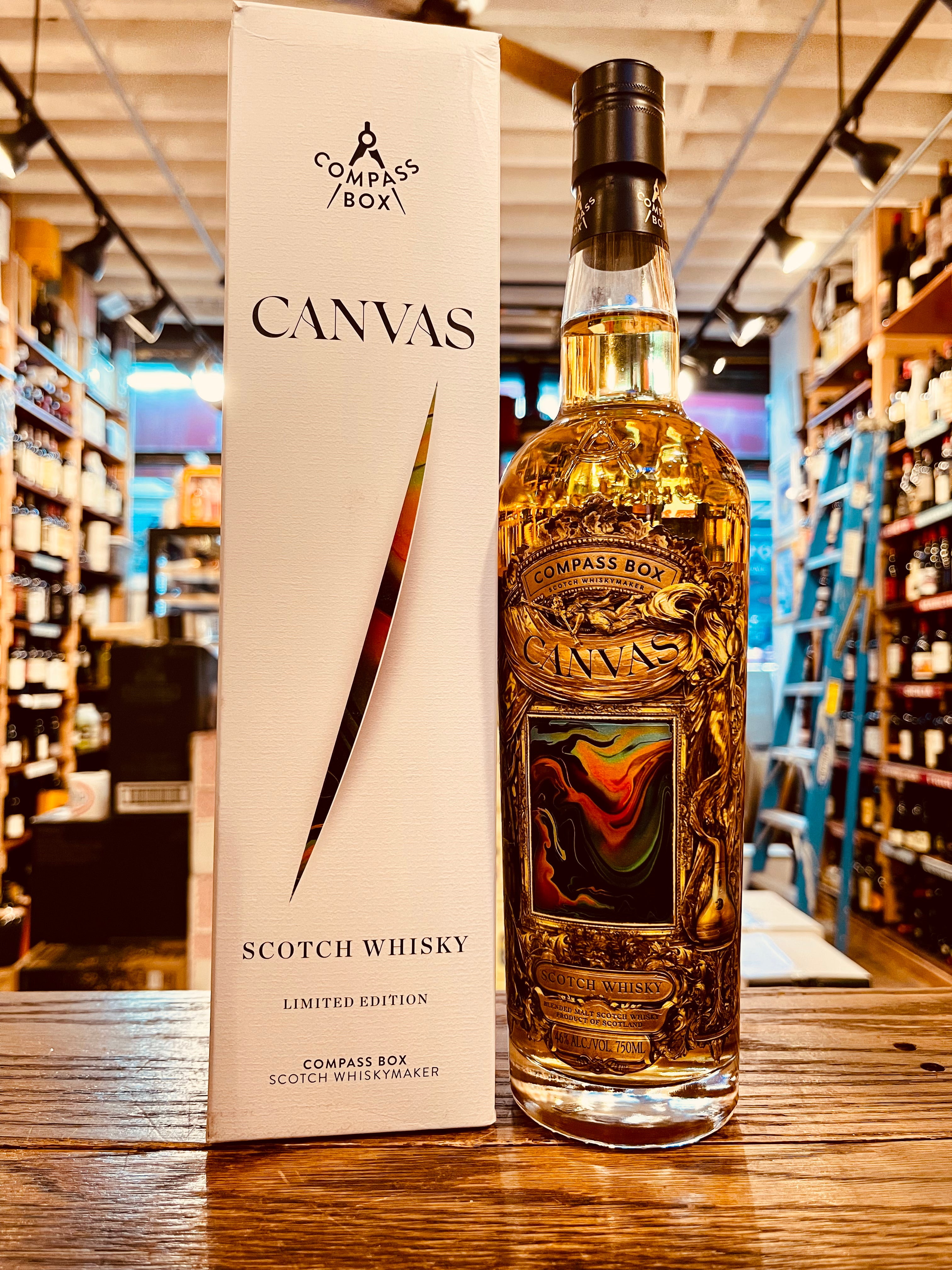Compass Box Canvas Scotch Whisky Limited Edition 750mL a white box next to a clear bottle with a multi colored label and a black top