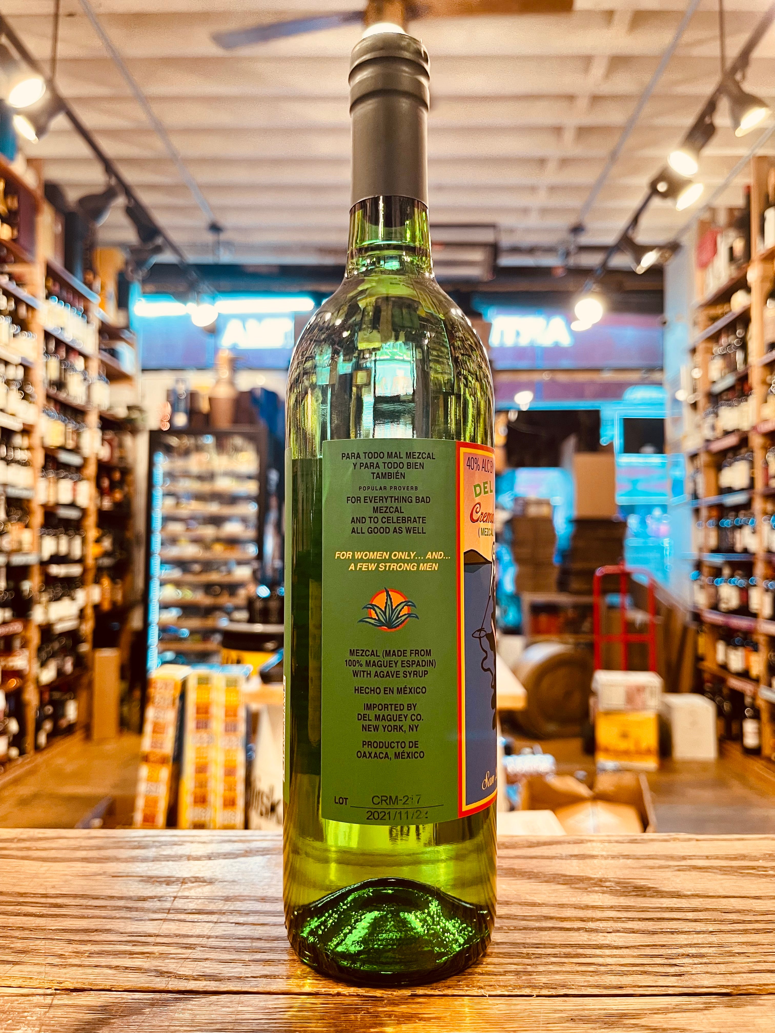 Del Maguey Crema de Mezcal 750mL back side of a clear green tall slender bottle with a multicolored label and black top
