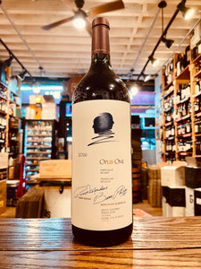 Opus One 2018 1.5L a large tall dark glass wine bottle with a large white label and rose gold top