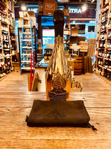 Armand de Brignac Champagne Brut Ace of Spades Gold 750 mL Tall golden bottle with a black top next to a black bag 