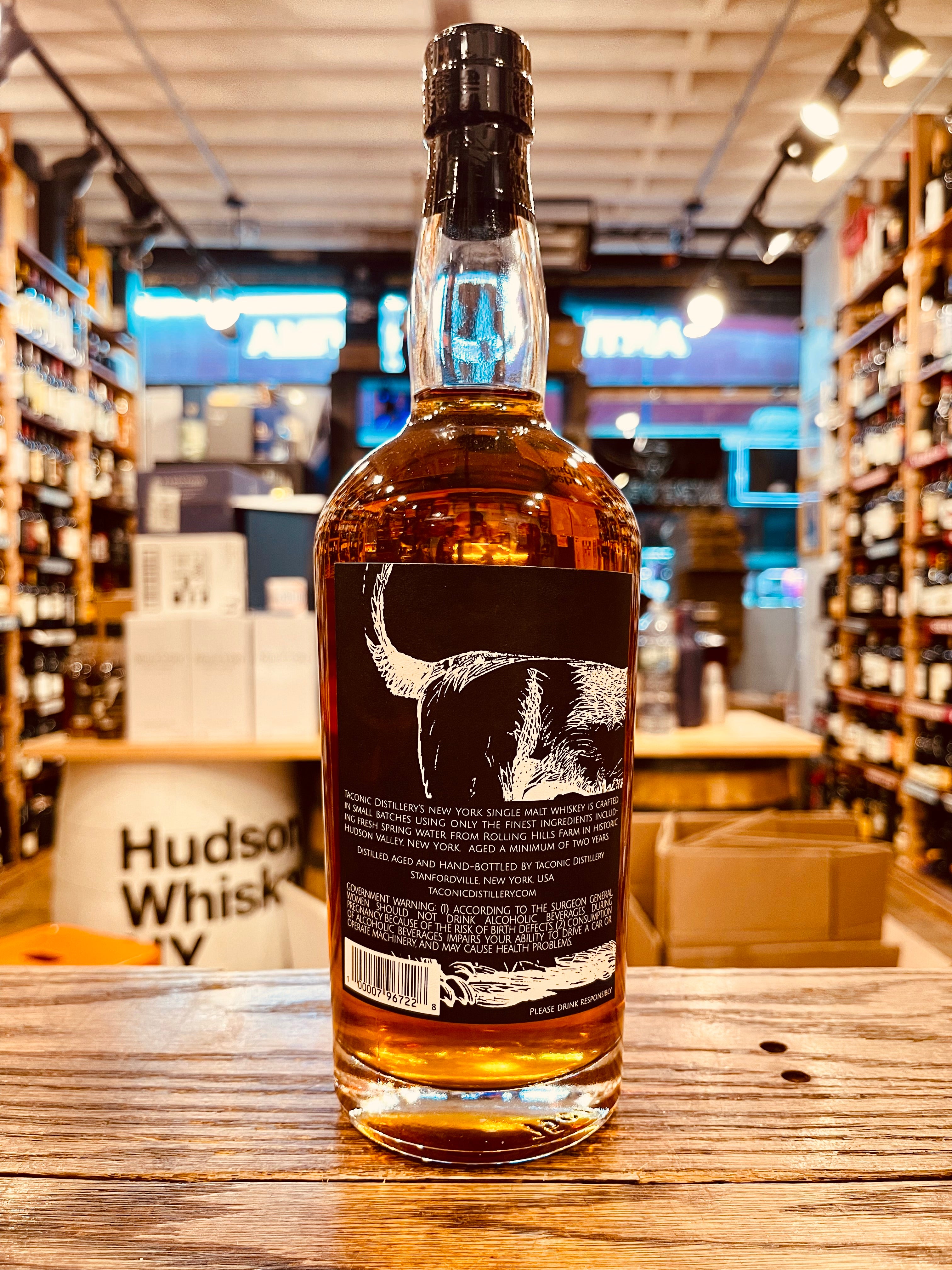 Taconic Distillery Single Malt Whiskey 750mL the backside of a high round shouldered clear glass bottle with a black label and the image of a dog hind quarters on it with a black top