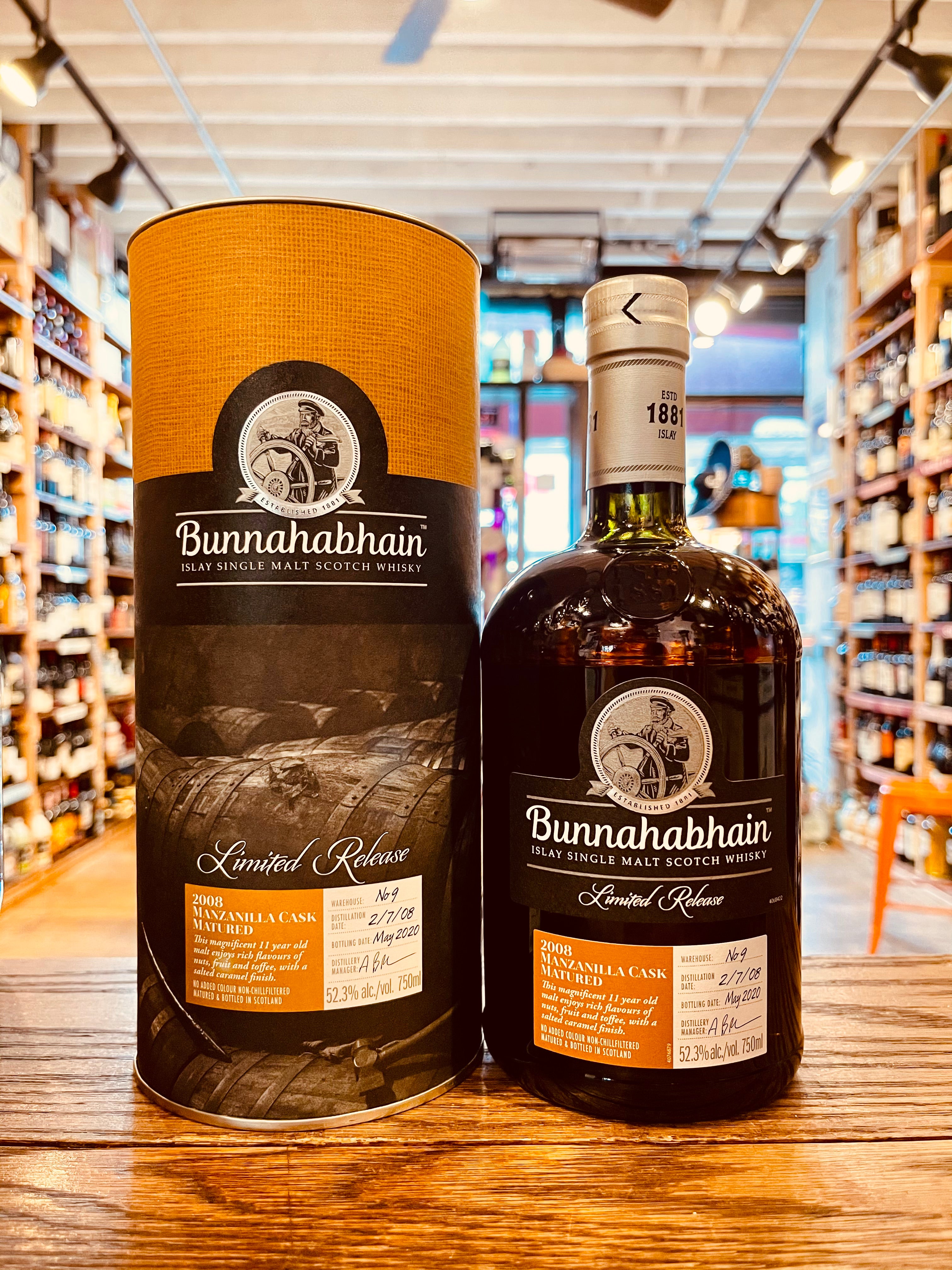 Bunnahabhain 2008 Manzanilla Islay Single Malt 750mL a yellow and dark canister next to a round shouldered dark bottle with a silver top