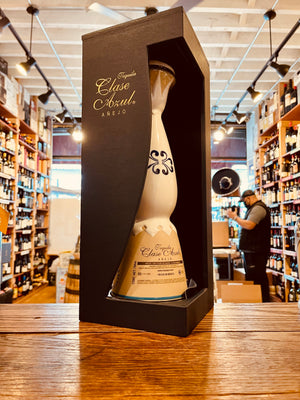 Clase Azul Anejo 750mL a tall white elegantly designed shapely bottle with a silver bell topper inside a dark blue open fronted box