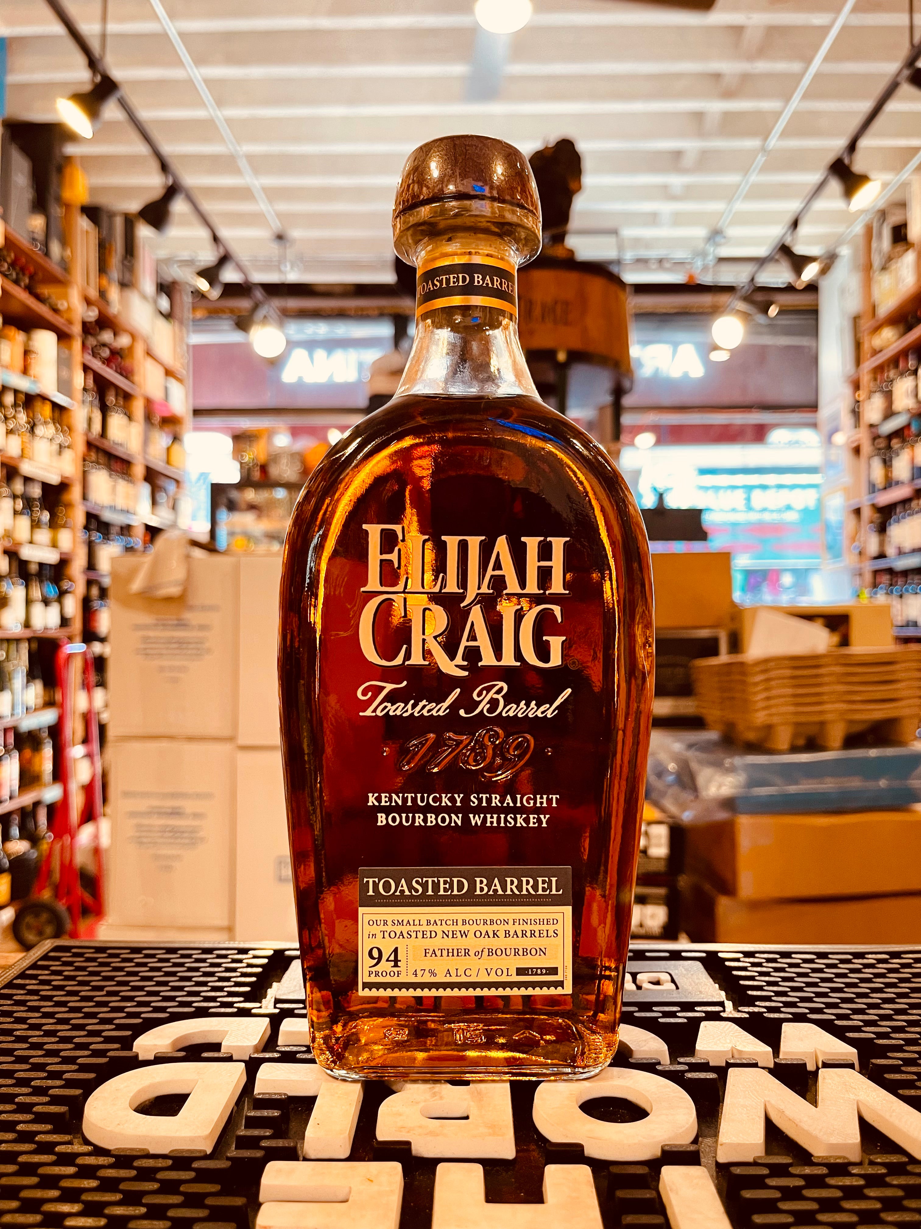 Elijah Craig Bourbon Toasted Barrel 750mL a flat clear round shouldered bottle with white lettering and a wooden top
