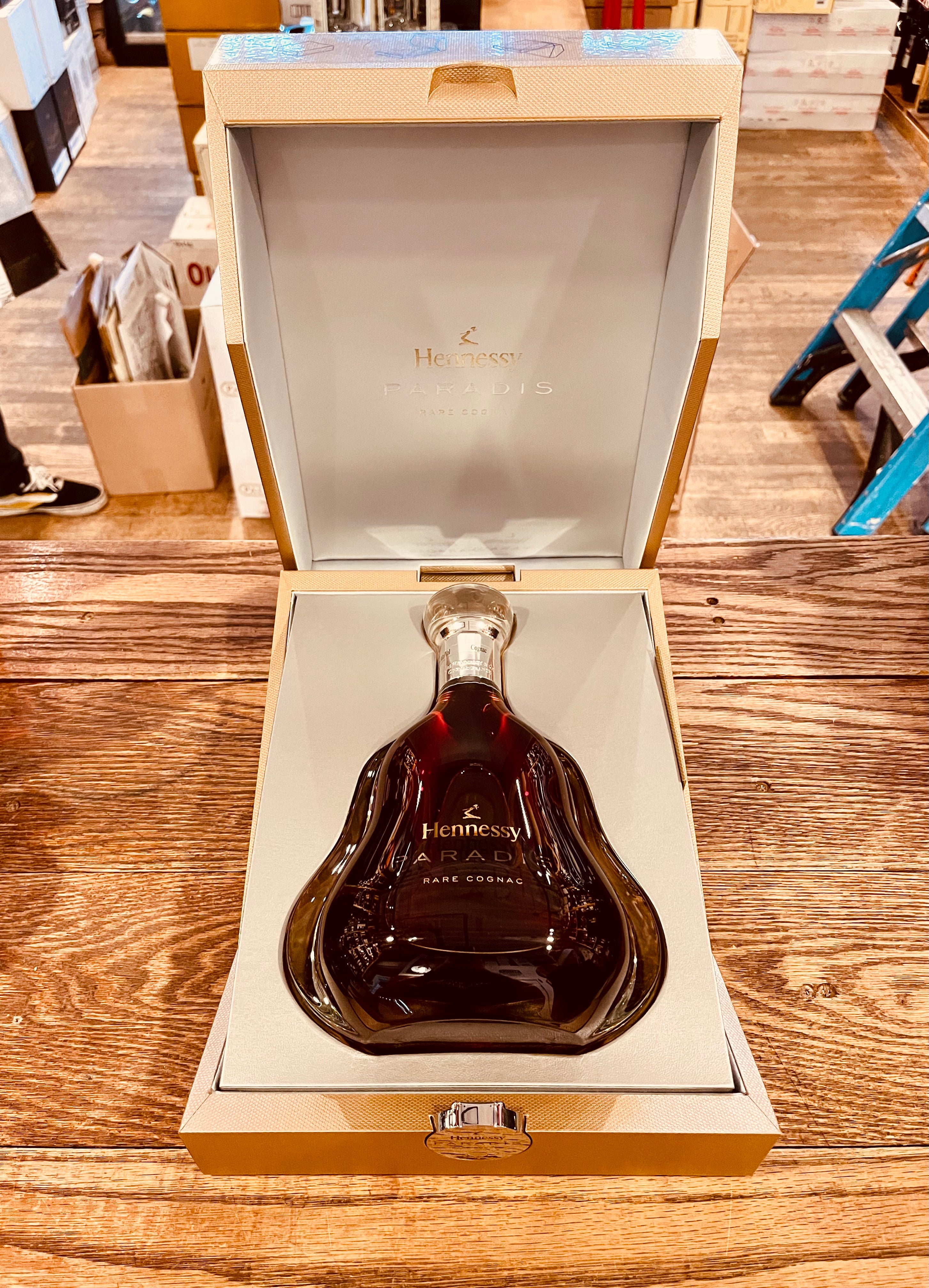 Hennessy Paradis 750mL an open golden box lined with white velvet with a shapely bottom heavy clear bottle inside of it that dawns gold lettering