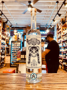 Los Siete Misterios Espadin Cuishe Ensamble 750mL a tall slender clear glass bottle with a white label with a skeleton head on it