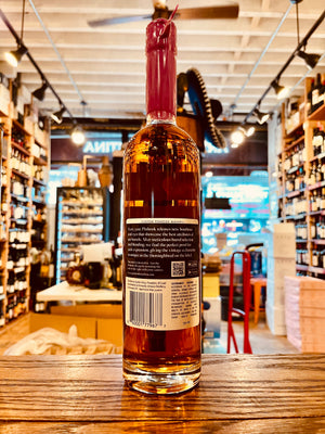 Pinhook 2023 High Proof Bourbon 750mL the backside of a tall clear glass bottle with a slender neck and a black label with a purple waxed top