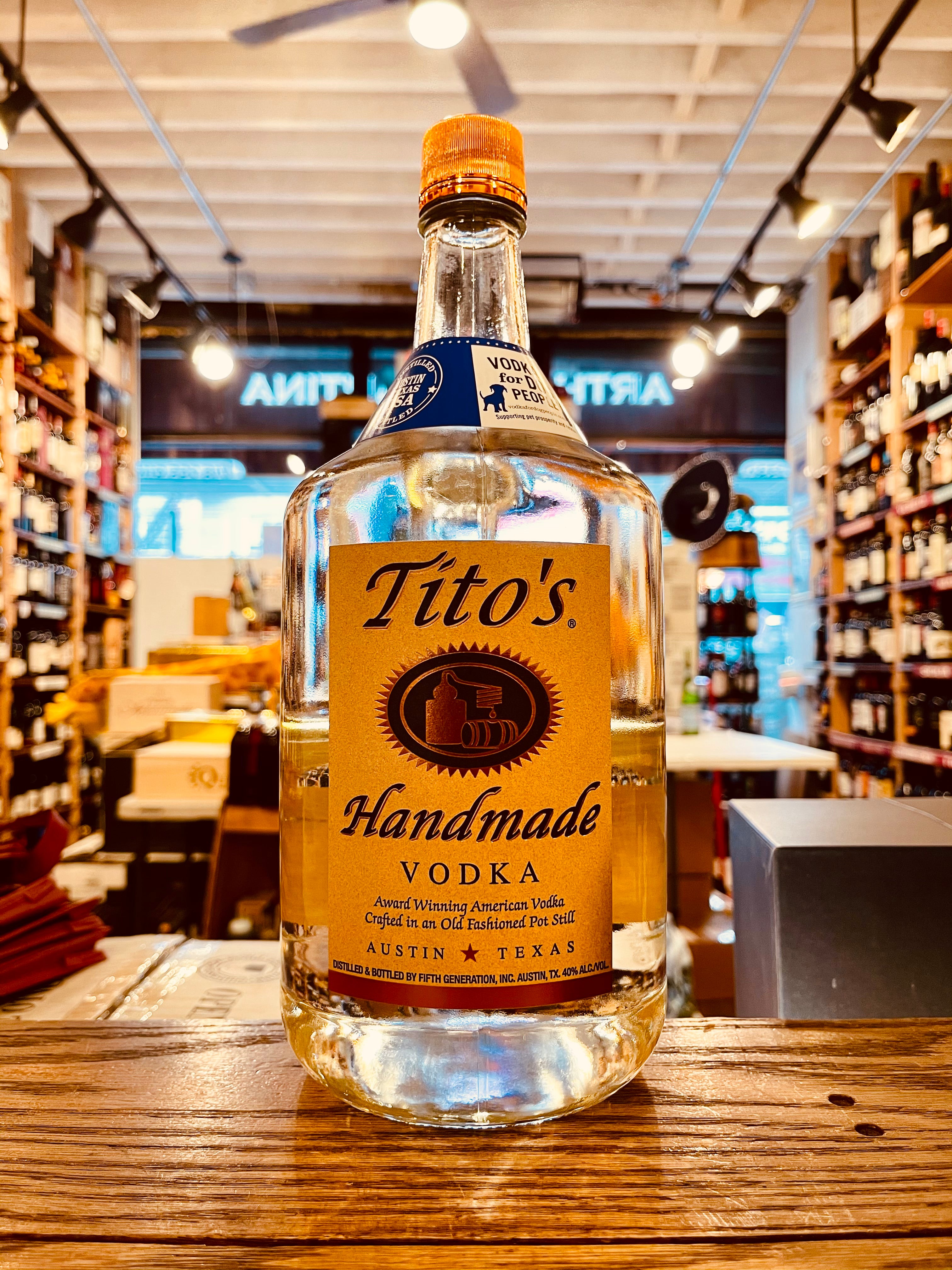 Tito's Handmade 1.75L Vodka a large glass robust clear bottle with a yellow label and a golden top