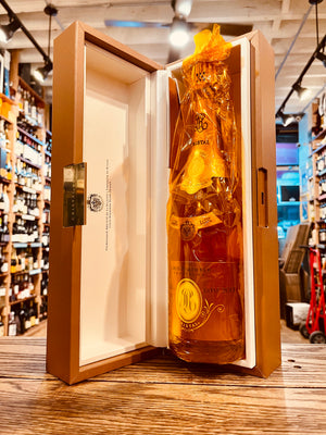 Roederer Cristal Rose 2013 750mL an open rose gold box lined with white holding a champagne bottle that is wrapped in a clear golden cellophane 