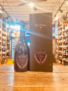 Dom Perignon Rose Gift 2006 750mL a dark champagne bottle with black and rose colored labeling next to a tall black box with black and rose labeling
