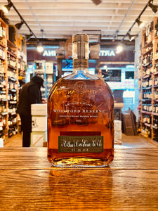 Woodford Reserve Bourbon Personal Selection 1L flat faced and with a label on the bottom and white lettering with a wooden top