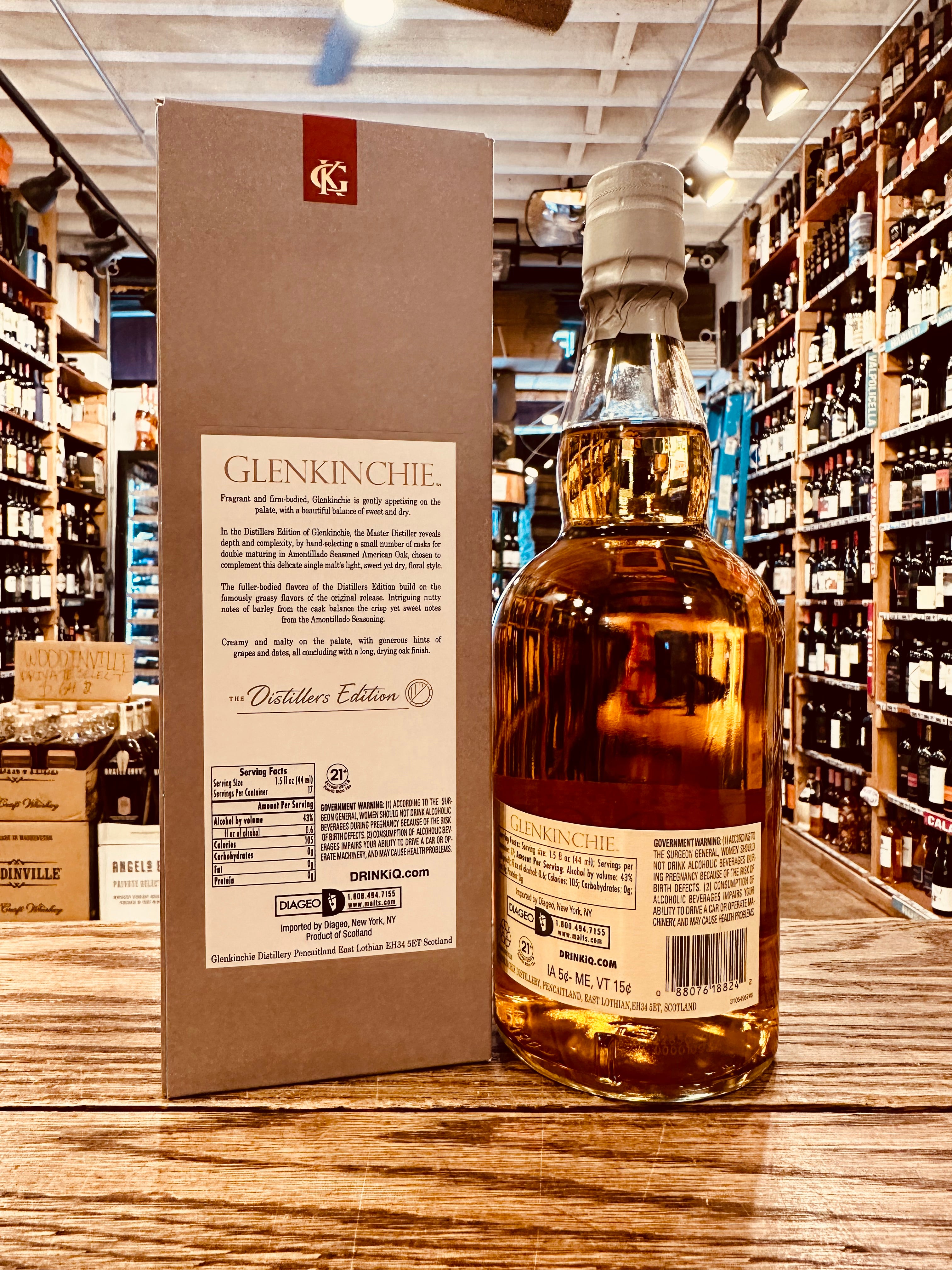 Glenkinchie Distillers Edition 750mL the backside of a  tall gray box with a white label next to a rounded clear bottle with a white label and gray top