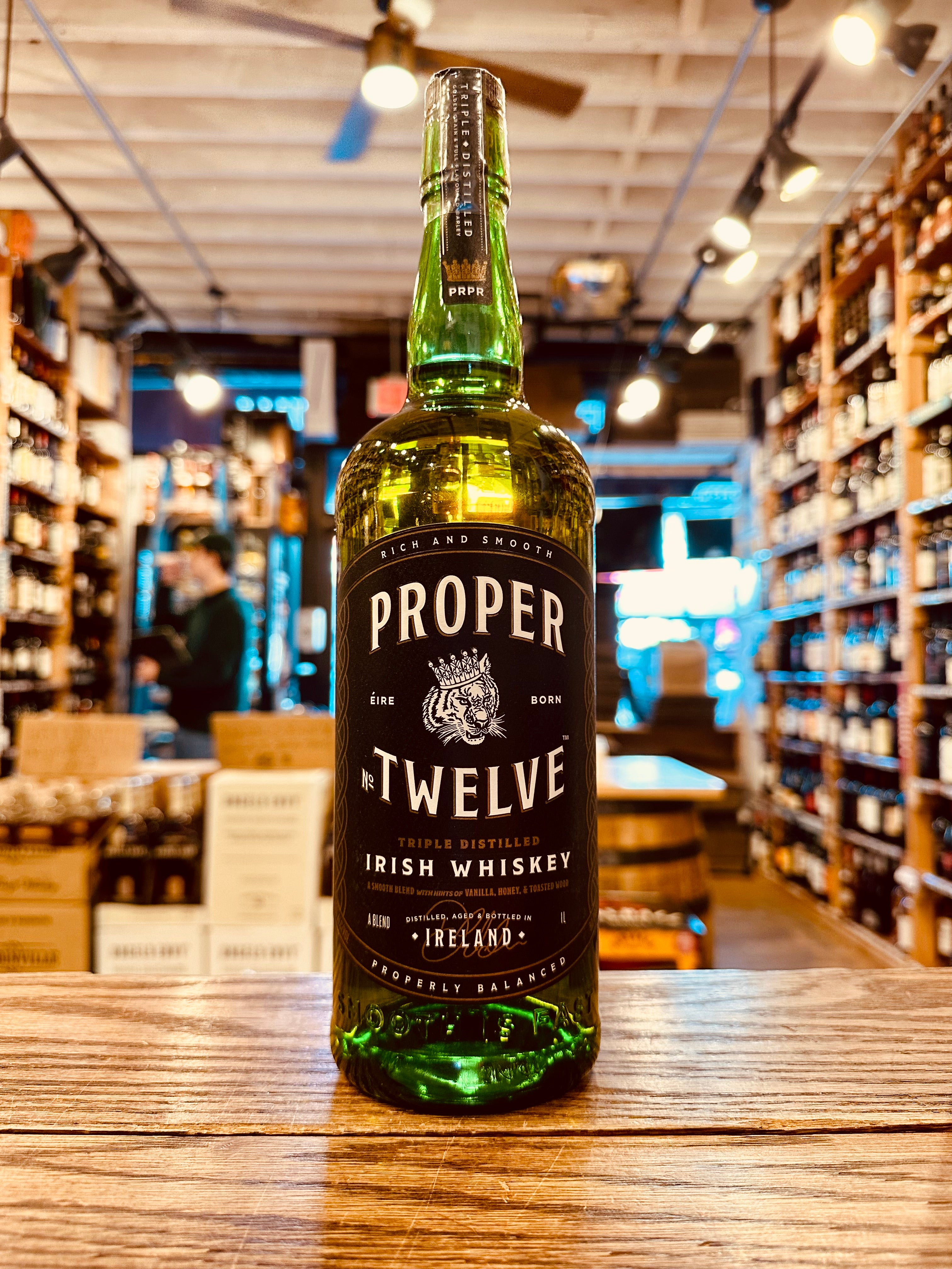 Proper Twelve 12 1L a tall round shouldered green glass bottle with a black label and black top