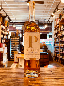 Penelope Bourbon 4 Grain 750mL a tall clear glass bottle with a long slender neck with a large white and gold label