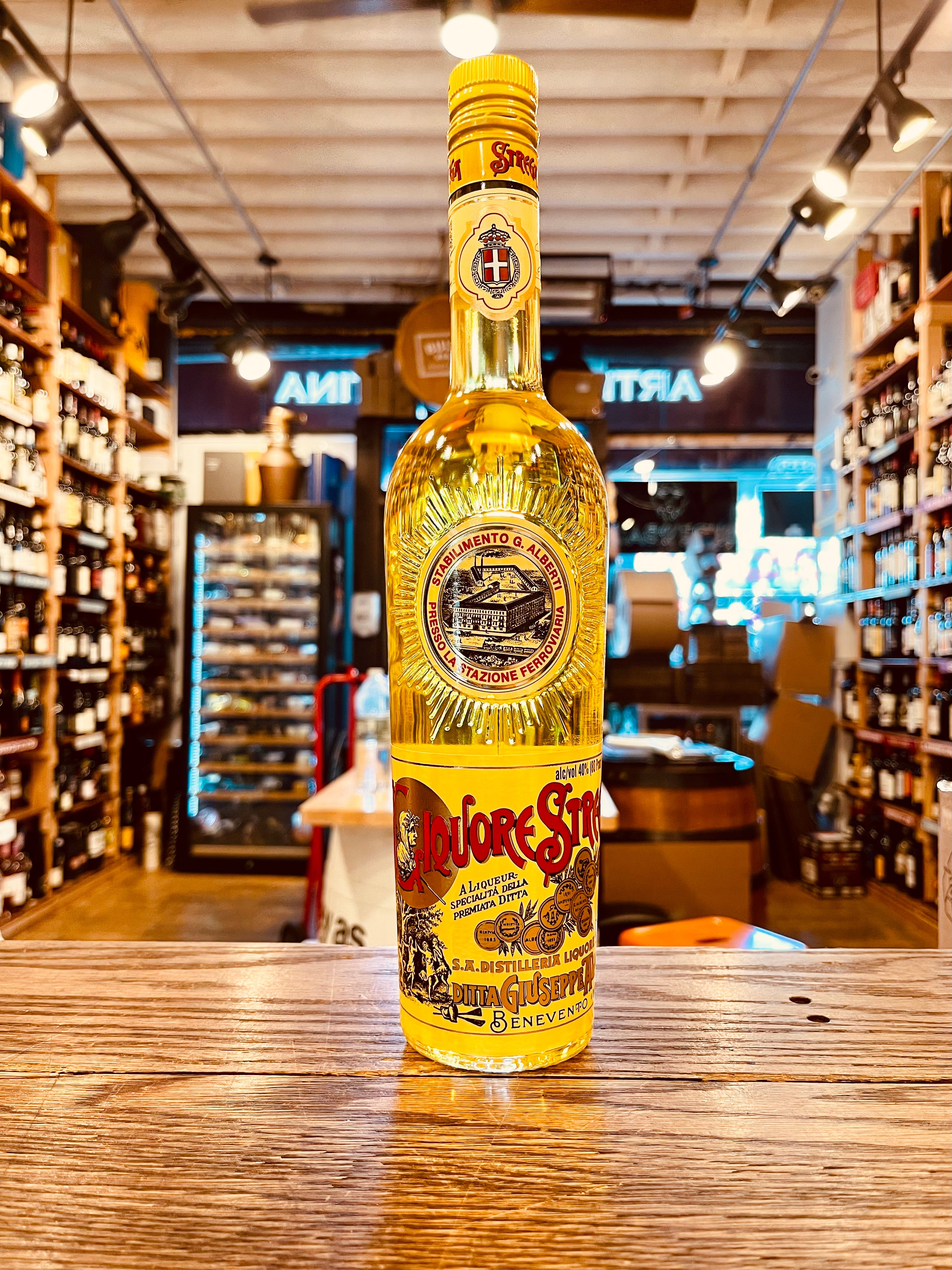 Strega Liquore 750mL a tall round shouldered long necked clear glass bottle with a yellow label and yellow top