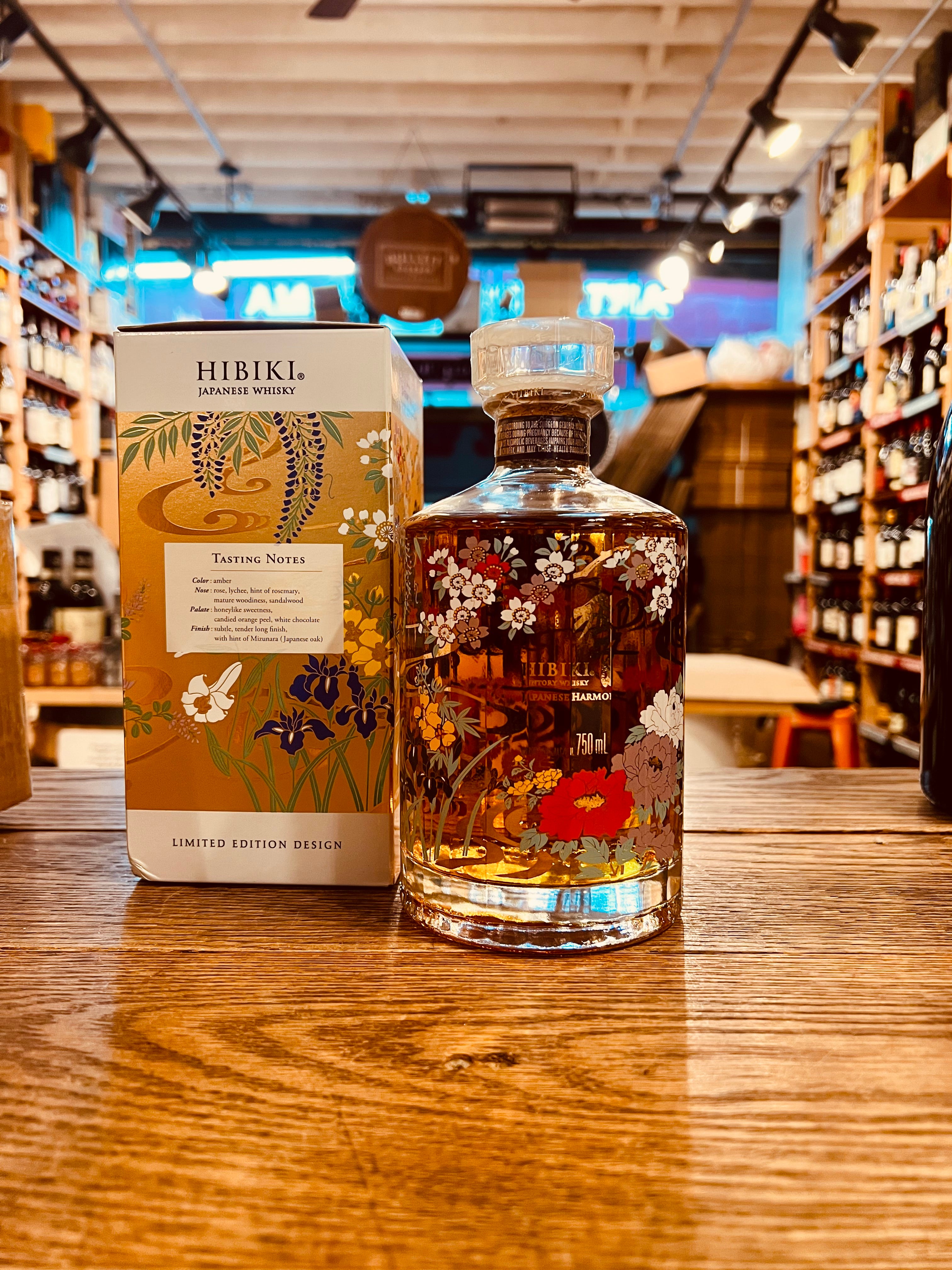 Hibiki Whiskey Limited Edition Harmony 750mL small squared white box with gold floral design next to a small circular clear bottle with floral imagery on it