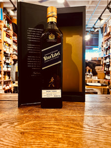 Johnnie Walker Blue Label New York Edition Scotch Whisky 750mL an open blue box with gold lining and white lettering inside with a tall square slender glass bottle with a golden top in front of it