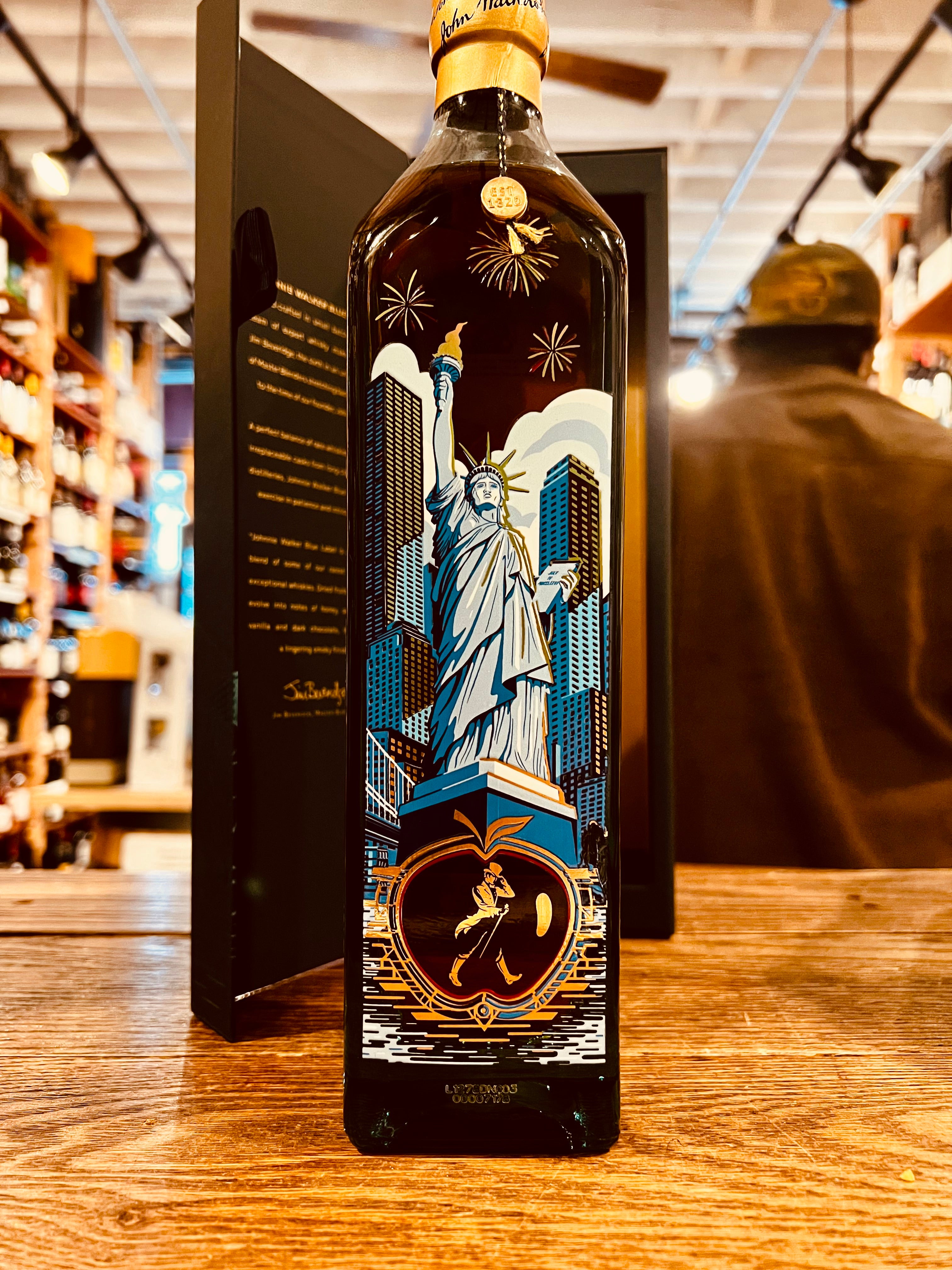Johnnie Walker Blue Label New York Edition Scotch Whisky 750mL an open blue box with a tall squared bottle in front of it that has the statue of Liberty imaged on the bottle