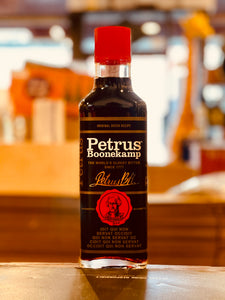 Petrus Boonekamp Amaro Bitter 750mL a flat surfaced squarish clear glass bottle with a black, gold, and red label with a large red top