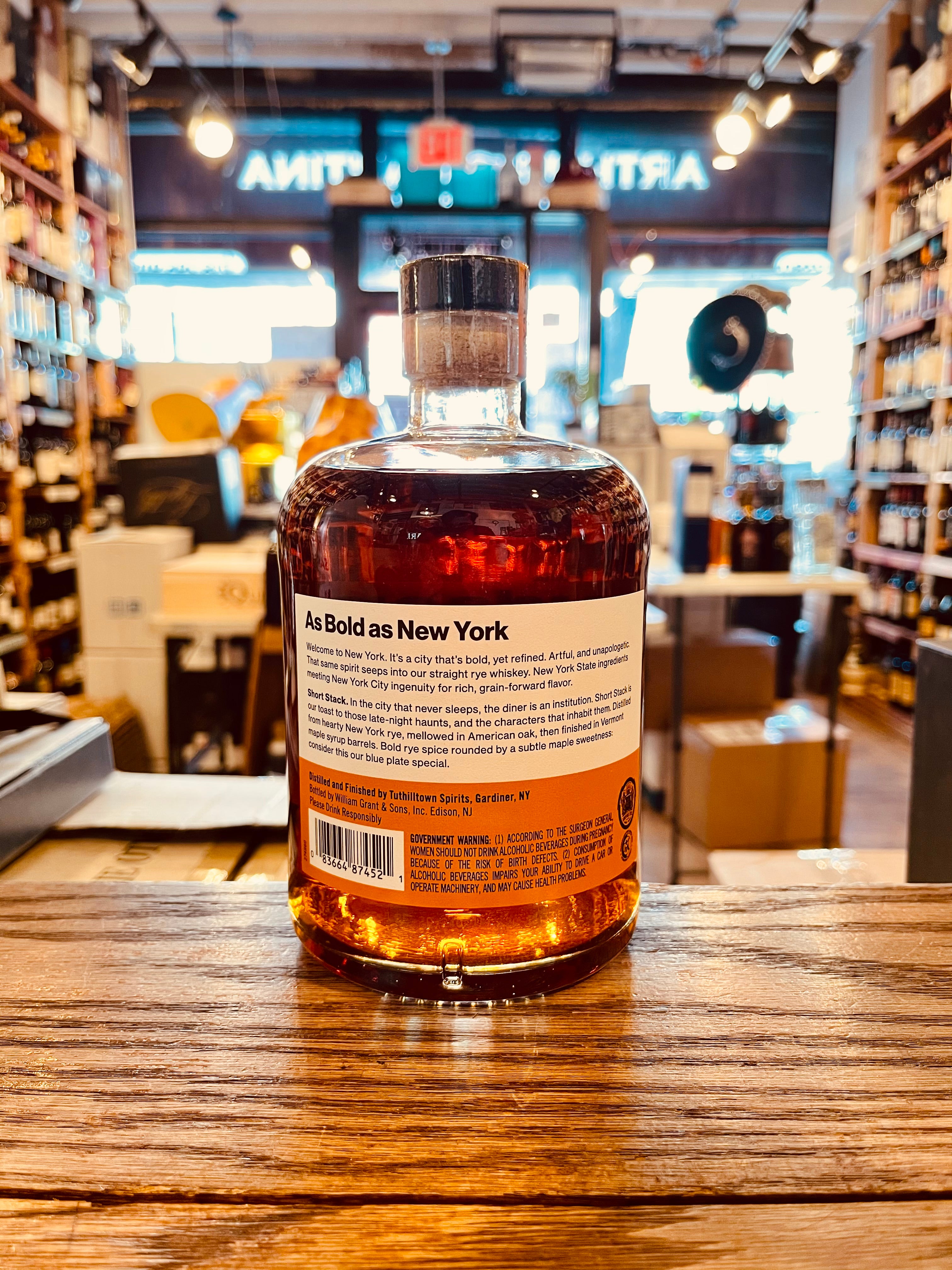 Hudson Whiskey NY Short Stack Rye 750mL the backside of a short squat rounded clear glass bottle with a white and orange label