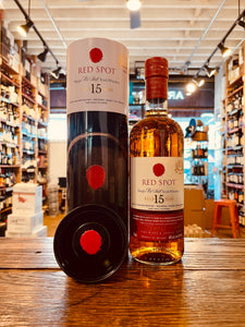 Red Spot Irish Whiskey 750mL a tall black and white cylinder tin next to a round high shouldered clear glass bottle with a white label and red spot on it with a red top