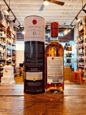 Red Spot Irish Whiskey 750mL the backside of a tall black and white cylinder tin next to a round high shouldered clear glass bottle with a white label and red spot on it with a red top