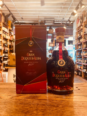 Gran Duque D'Alba Gran Reseva 750mL a red box with the image of a man's face on it next to a small squat rounded clear bottle with a yellow label and red top
